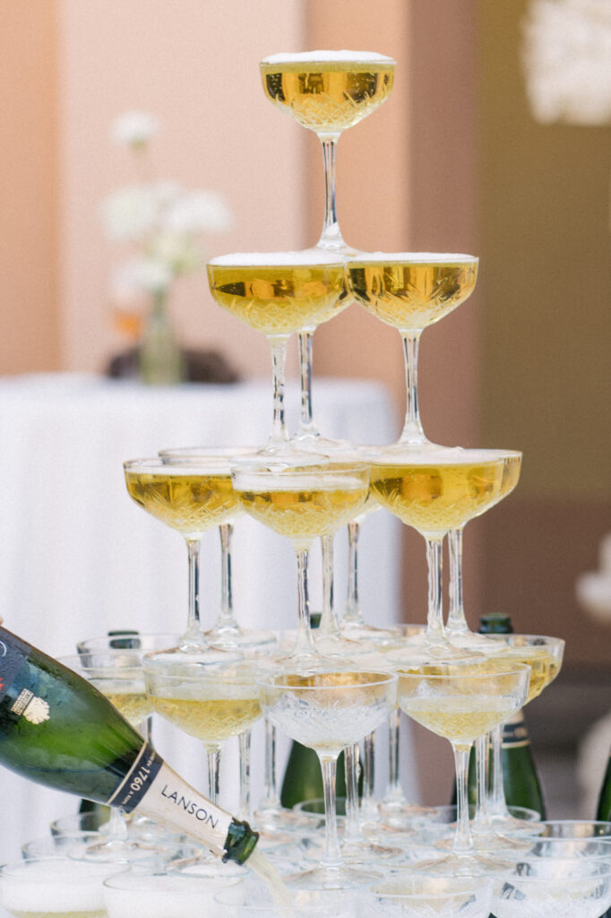 Ein Sektturm, in dessen oberstes Glas bei einer eleganten Veranstaltung, die von Julia Weiß' Soireen am Comer See inspiriert ist, Sekt eingegossen wird.
