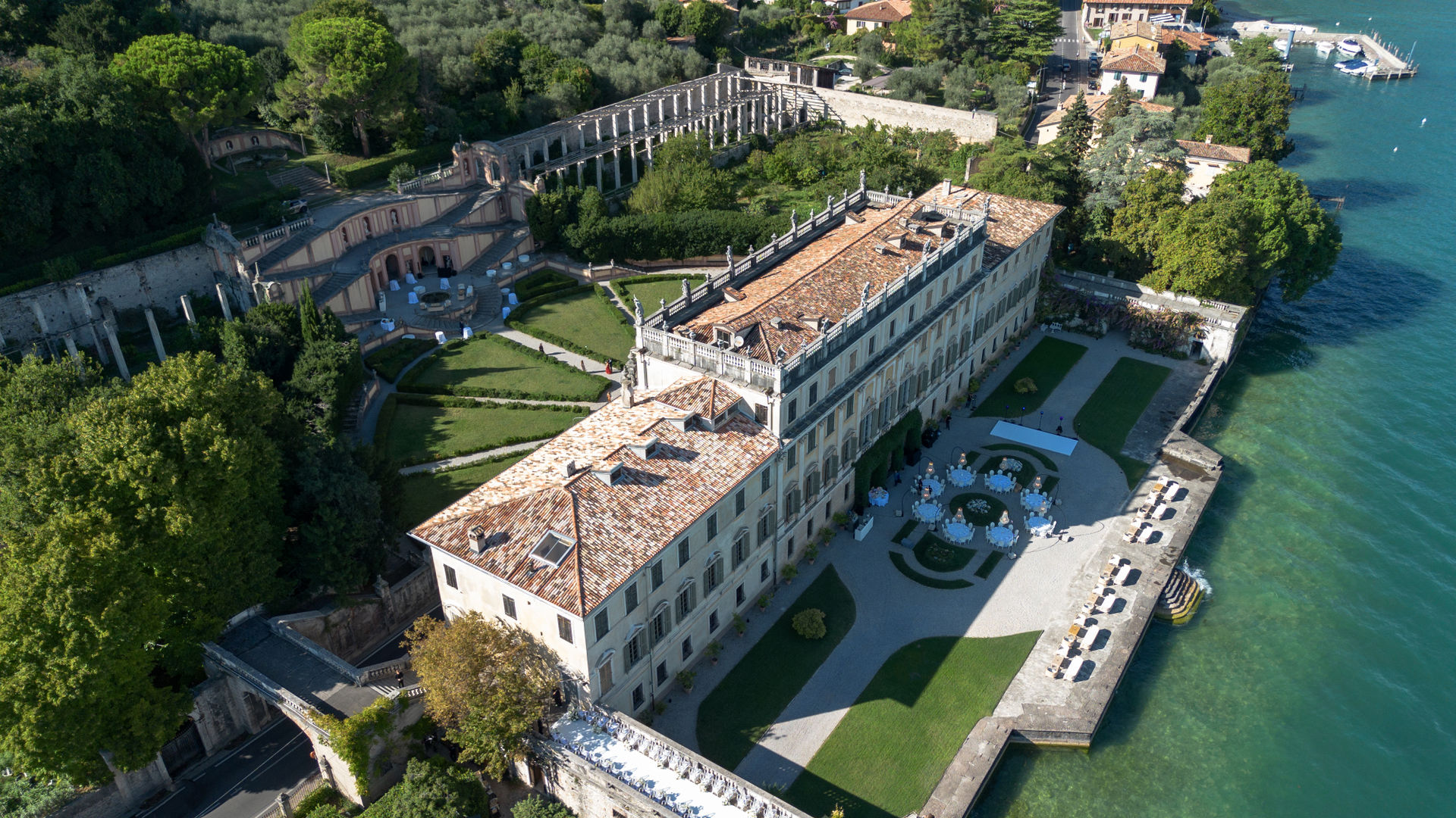Luftaufnahme einer eleganten Villa mit Terrassengärten am Ufer eines italienischen Sees.