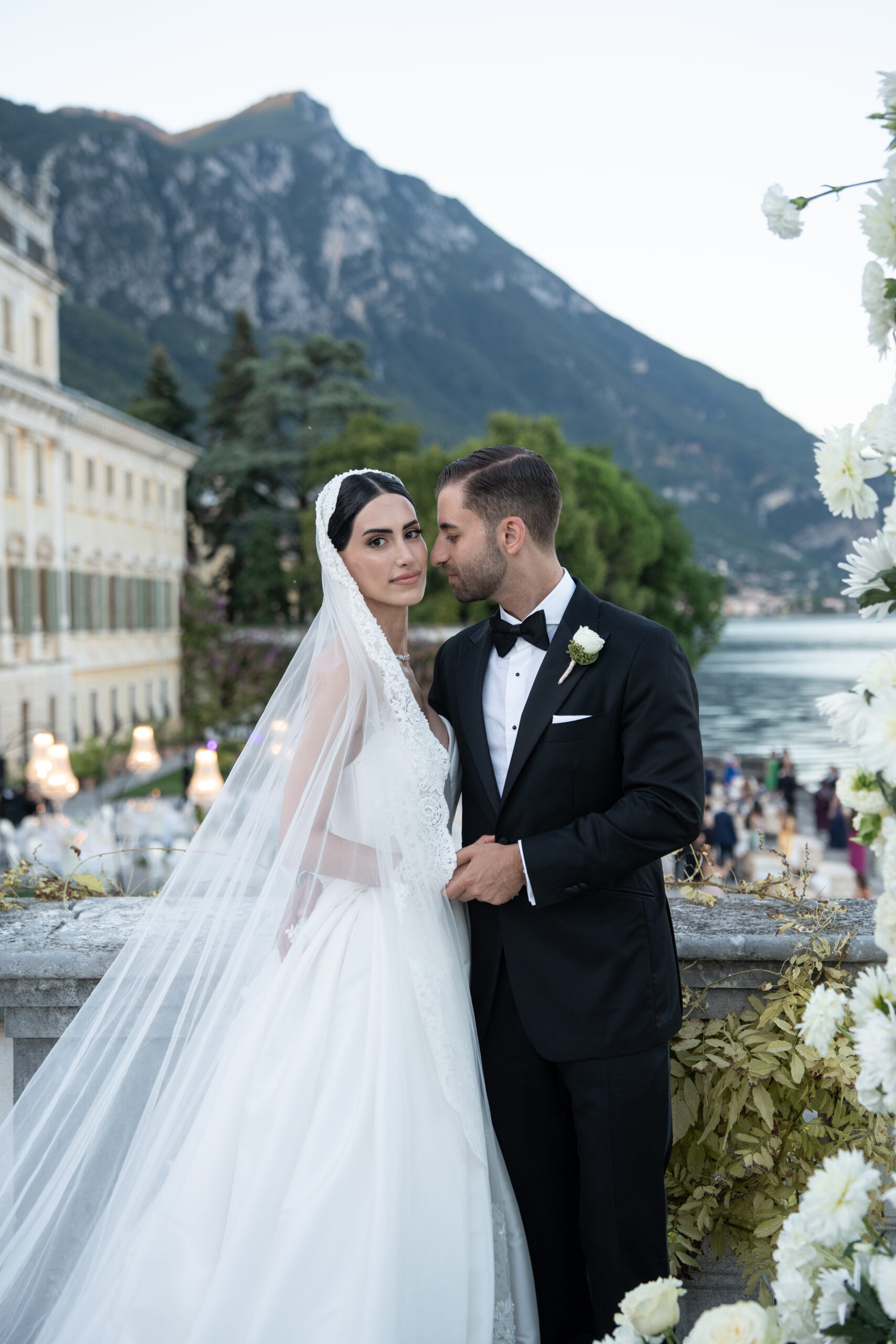 Braut und Bräutigam in Hochzeitskleidung stehen bei einer exklusiven Hochzeit in der Toskana, Italien, an einem See.