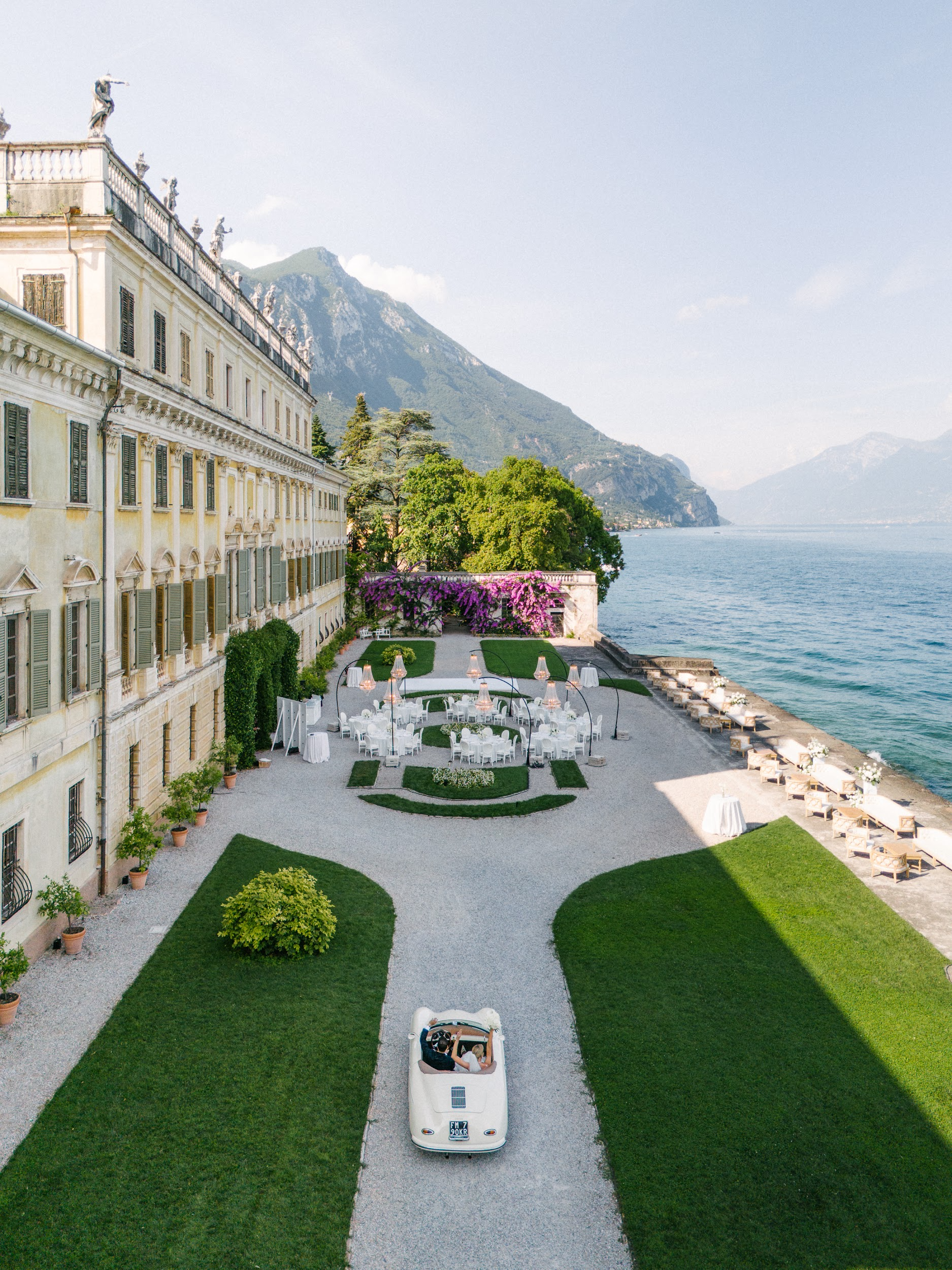 Ein weißer Oldtimer fährt auf eine Hochzeitsfeier in einer italienischen Villa am See zu.
