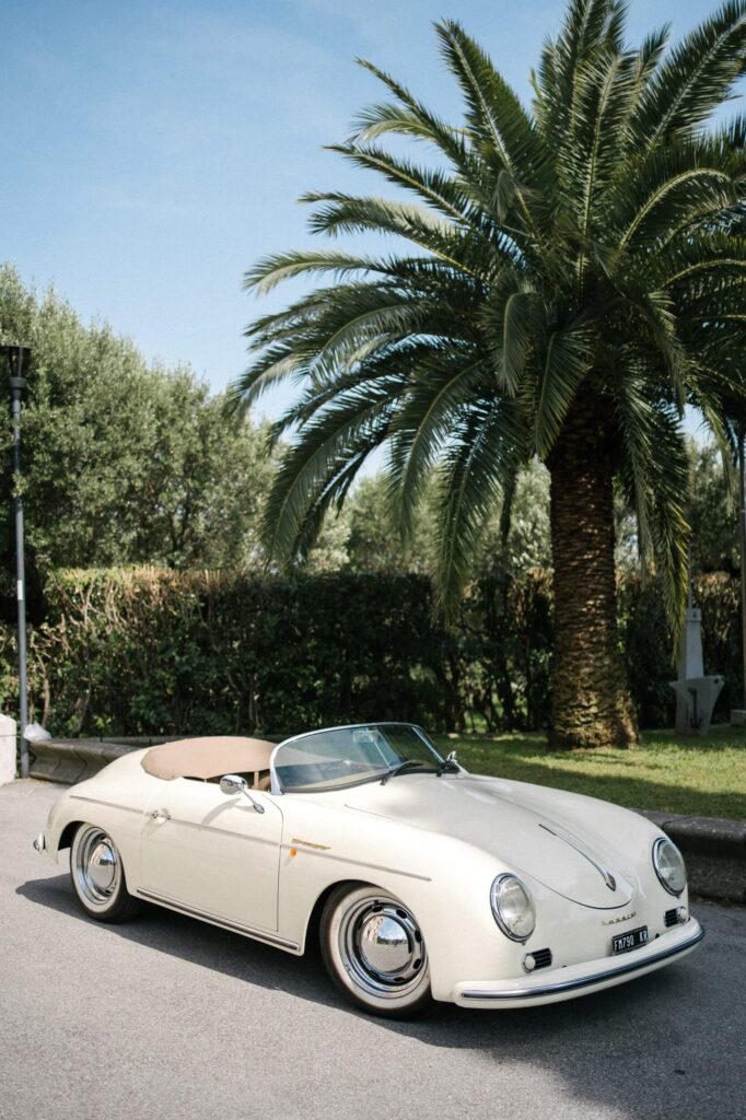 Cremefarbenes Oldtimer-Cabriolet unter Palmen – Dolce-Vita-Vibe in Italien.