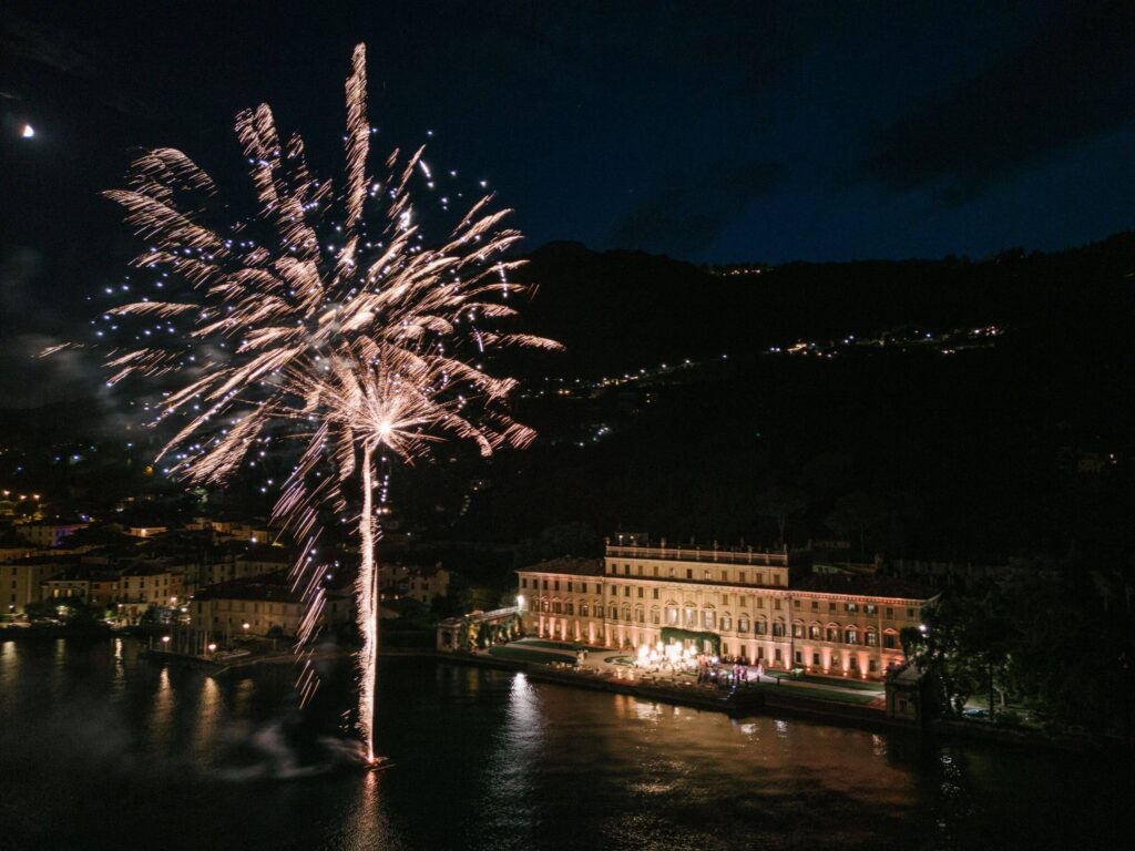Ein spektakuläres Feuerwerk über einer beleuchteten Villa am Comer See bei Nacht – ein Wow-Moment einer Luxushochzeit in Italien.